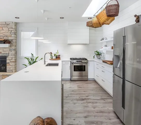 Modern kitchen featuring white cabinetry, stainless steel appliances, a built-in wine refrigerator, and wood-finish flooring