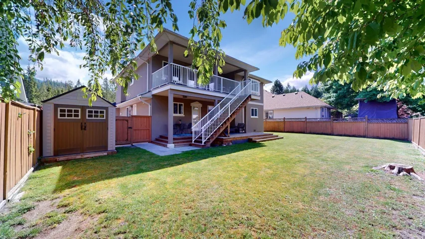 Back of property with a storage shed, an outdoor structure, stairs, a deck, and stucco siding