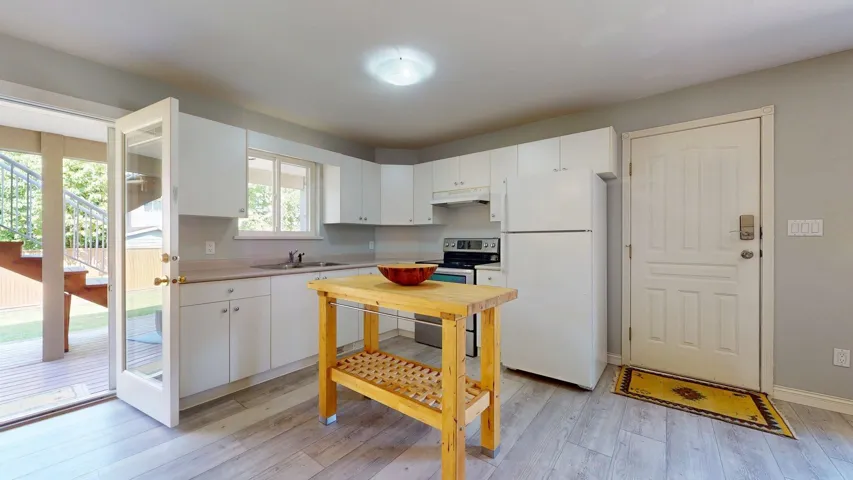 Kitchen with freestanding refrigerator, stainless steel electric range, under cabinet range hood, a sink, and light countertops