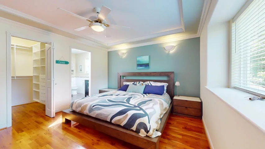 Bedroom with light wood-type flooring, a walk in closet, ornamental molding, ensuite bath, and a closet