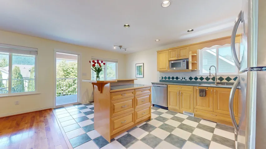 Kitchen featuring appliances with stainless steel finishes, a sink, light brown cabinets, a center island, and backsplash
