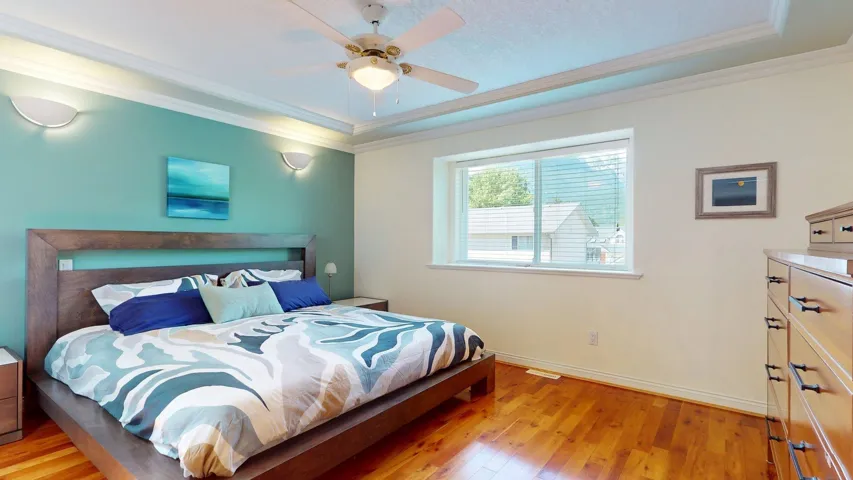 Bedroom with light wood-style floors, baseboards, crown molding, and ceiling fan