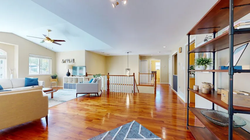 Living area featuring ceiling fan, wood finished floors, baseboards, and lofted ceiling
