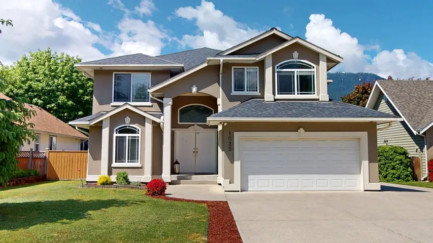 Traditional-style home featuring stucco siding, driveway, a garage, and a shingled roof