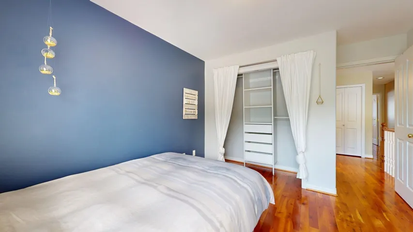 Bedroom with wood finished floors, a closet, and baseboards