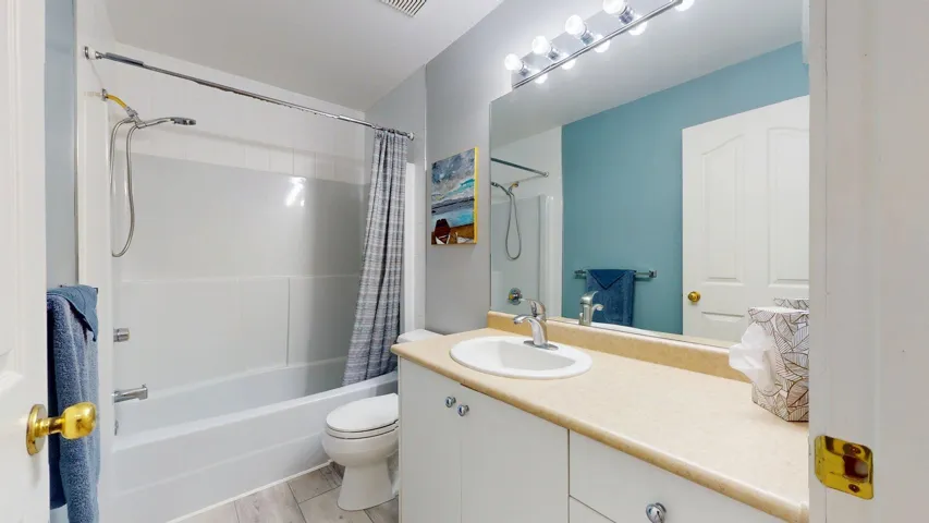 Full bath with shower / bath combo, vanity, and toilet