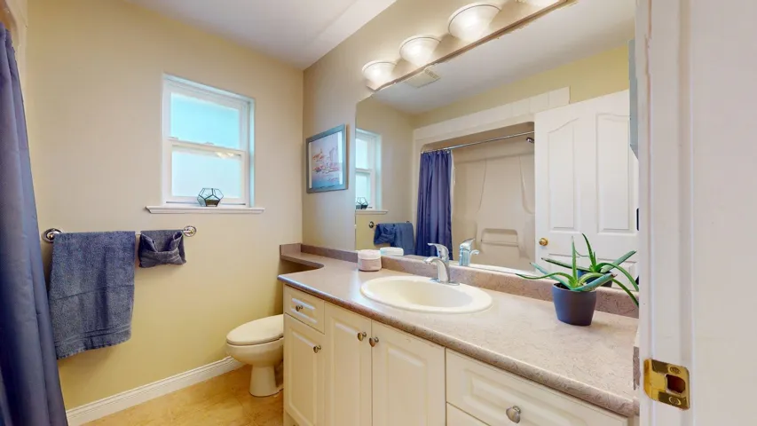 Full bath with toilet, baseboards, curtained shower, vanity, and tile patterned flooring