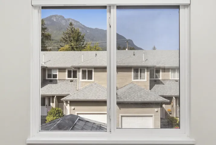 Sliding window with white frame and sill showcasing a mountain backdrop
