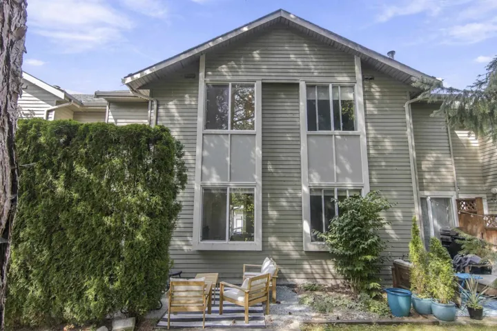Two-story siding exterior featuring vertical window accents and a landscaped rear patio
