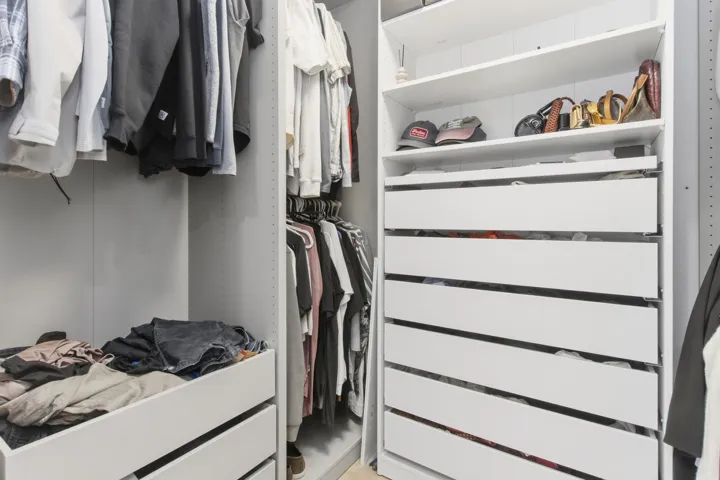 Custom storage system featuring floor-to-ceiling white cabinetry, integrated shelving units, and multiple pull-out storage drawers
