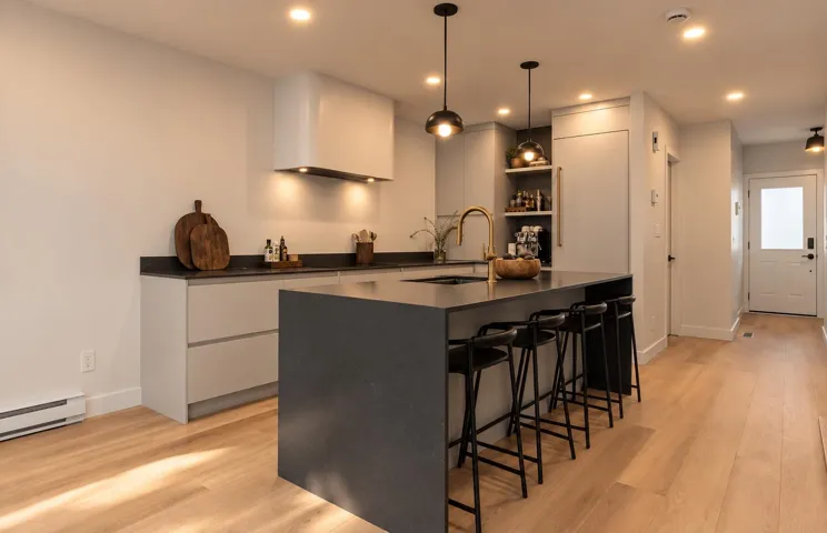 Kitchen featuring flat-panel cabinetry, a central island with a dark solid-surface countertop, a curved range hood, recessed lighting, and wood-finish flooring
