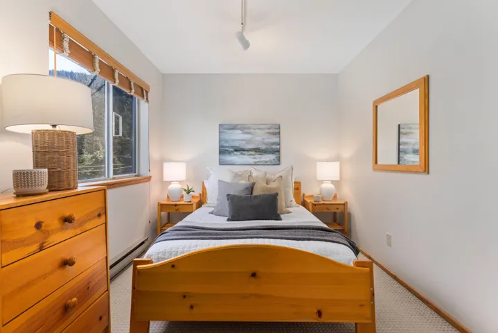 Carpeted bedroom with baseboard heating, multiple windows, track lighting, and baseboards