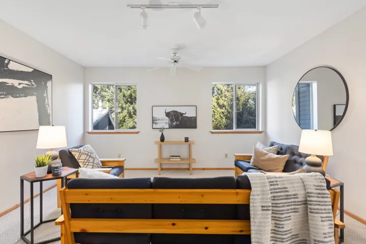 Carpeted living area featuring track lighting, baseboards, and ceiling fan