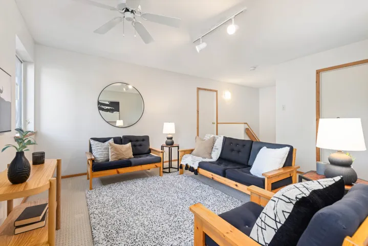 Living room with track lighting, ceiling fan, baseboards, and carpet