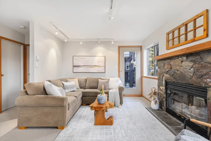 Living area featuring light carpet and a stone fireplace