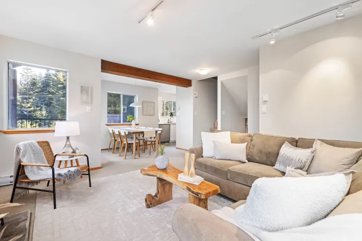 Living area featuring a baseboard heating unit, beam ceiling, carpet, and track lighting
