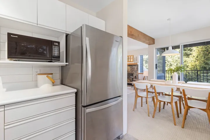 Kitchen featuring decorative light fixtures, white cabinetry, freestanding refrigerator, black microwave, and a fireplace