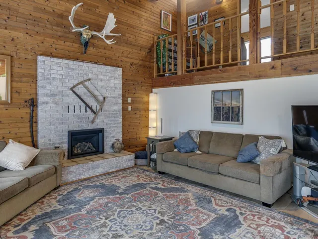 Living room featuring a vaulted ceiling, cedar walls, and a gas fireplace