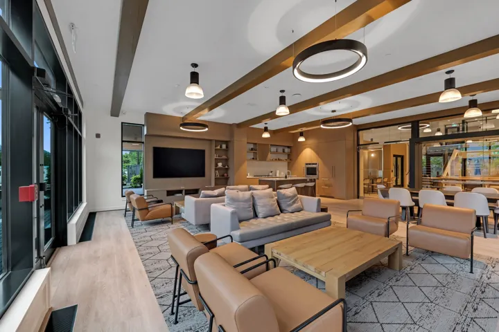 Spacious open-concept interior featuring light wood-finish flooring, exposed ceiling beams, and integrated modern lighting fixtures