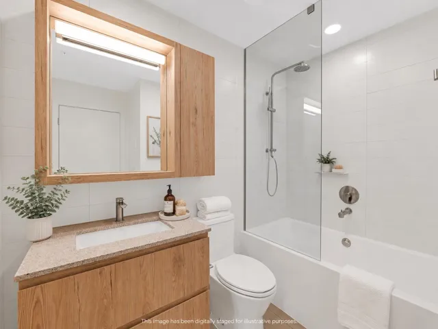 Bathroom featuring a wood-finish vanity with an integrated sink and light-colored countertop