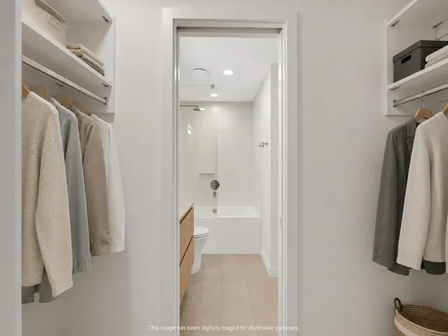 Walk-through closet featuring built-in shelving, hanging rods, and an entryway to a full bathroom