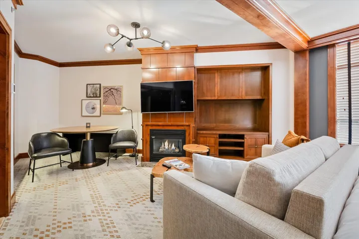 Living room with ornamental molding, a glass covered fireplace, and light colored carpet
