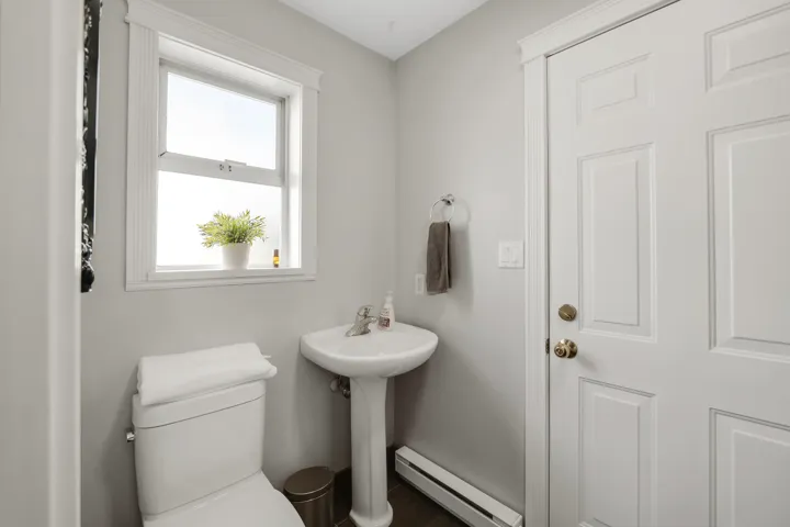 Powder room featuring a pedestal sink, white paneled door, and a single-hung window with detailed trim