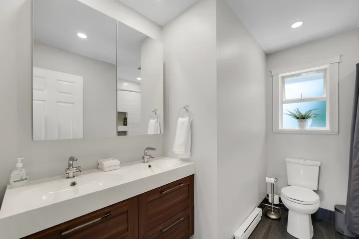 Bathroom featuring a double vanity with an integrated sink, wood-finish cabinetry, and recessed lighting
