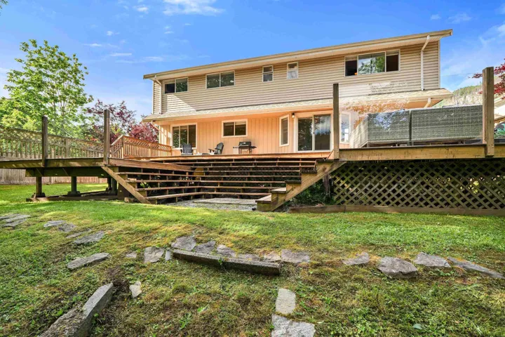 Multi-level wooden deck featuring extensive railing, lattice skirting, and multiple access points to the home's rear