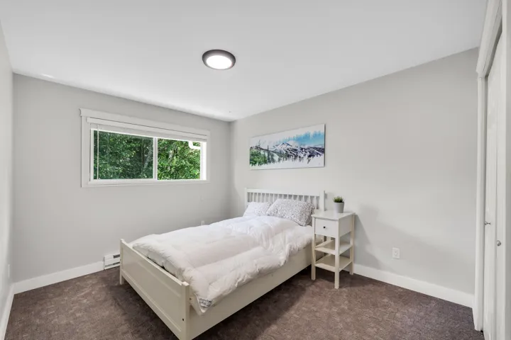 Bedroom featuring light gray walls, brown carpet flooring, and a single window with white trim