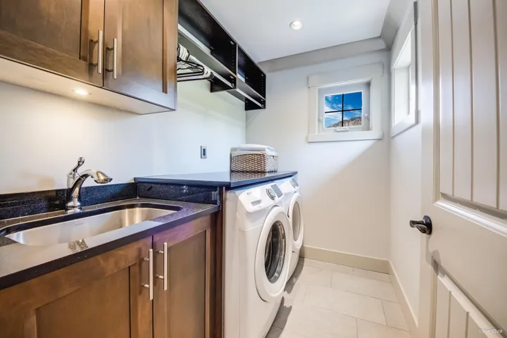 Clothes washing area with recessed lighting, washer and dryer, cabinet space, a sink, and baseboards