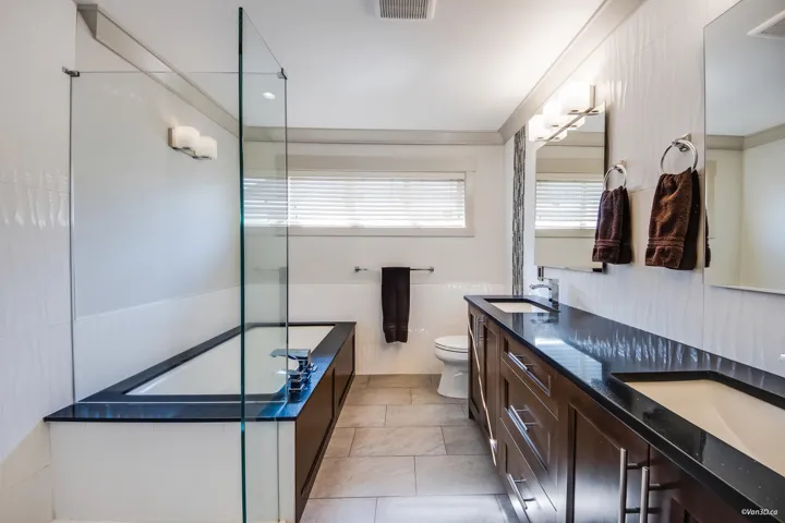 Full bathroom with a tub, double vanity, toilet, a sink, and visible vents