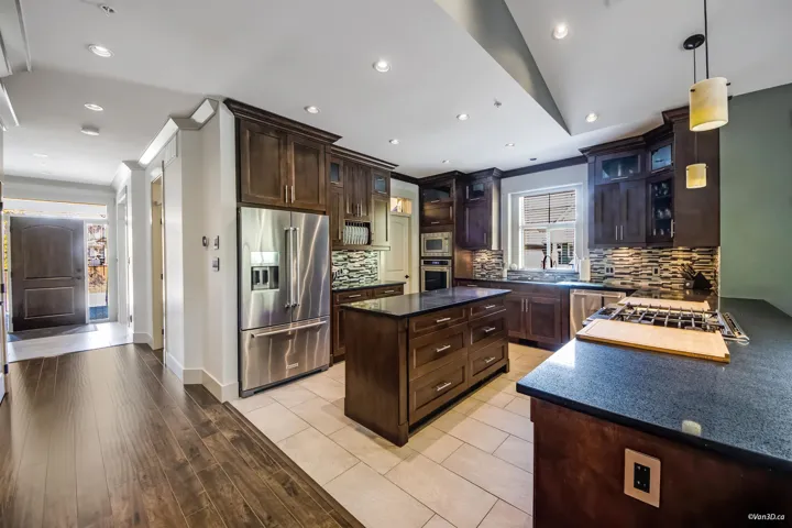 Kitchen with a center island, dark brown cabinets, backsplash, and appliances with stainless steel finishes