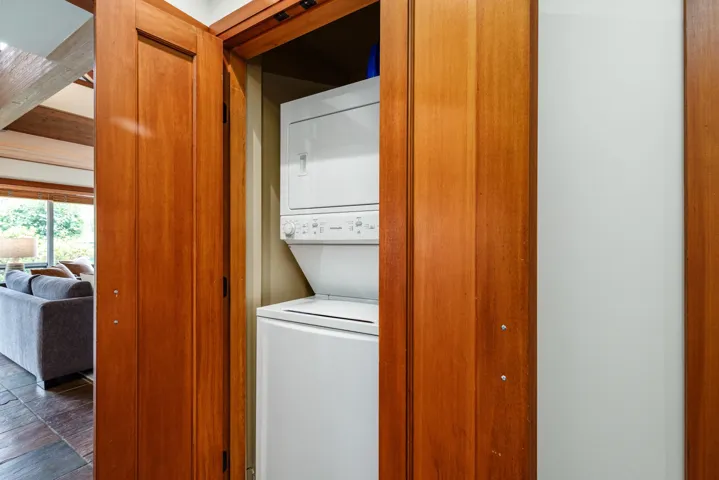 Integrated laundry closet featuring a stackable washer and dryer unit, complemented by warm wood bi-fold doors