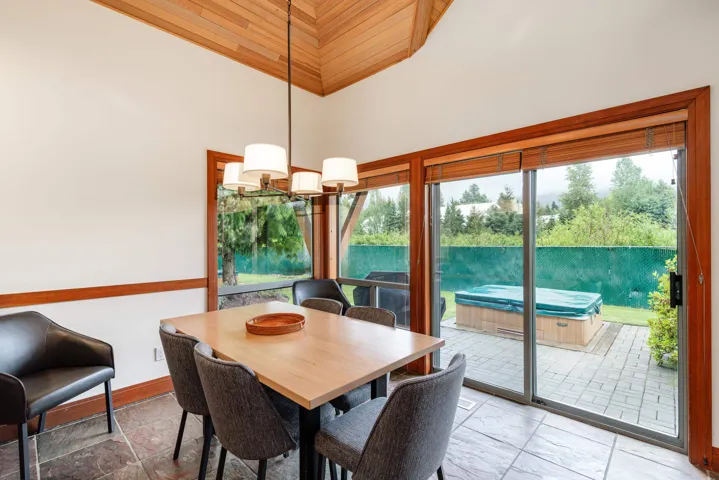 Dining area featuring a vaulted wood-paneled ceiling, chandelier lighting, and tile flooring