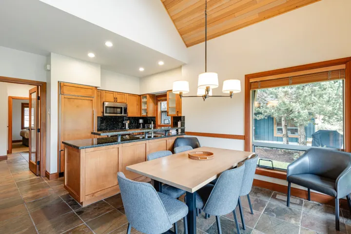 Kitchen and dining area featuring vaulted ceilings with wood-paneling, slate tile flooring, and a large window