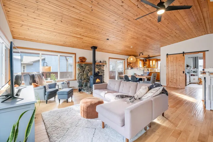 Living area with a barn door, a vaulted wood ceiling, a wood stove, and healthy amount of natural light