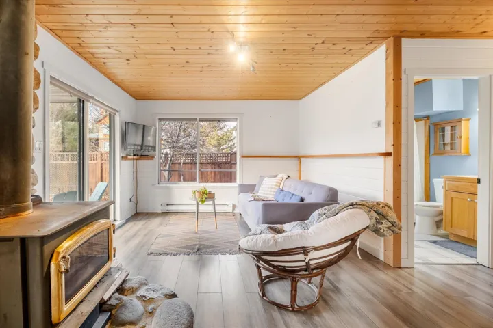 Living area featuring a wood stove, wooden ceiling,