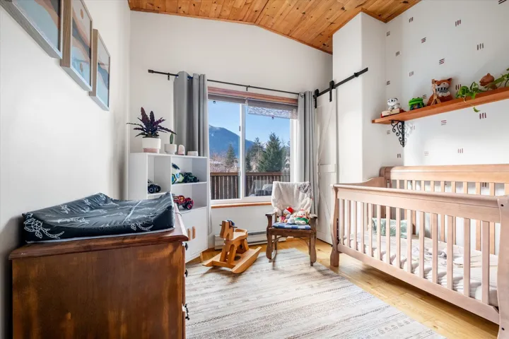 Bedroom featuring a crib, a mountain view, a barn door, a vaulted wood ceiling, and light wood finished floors