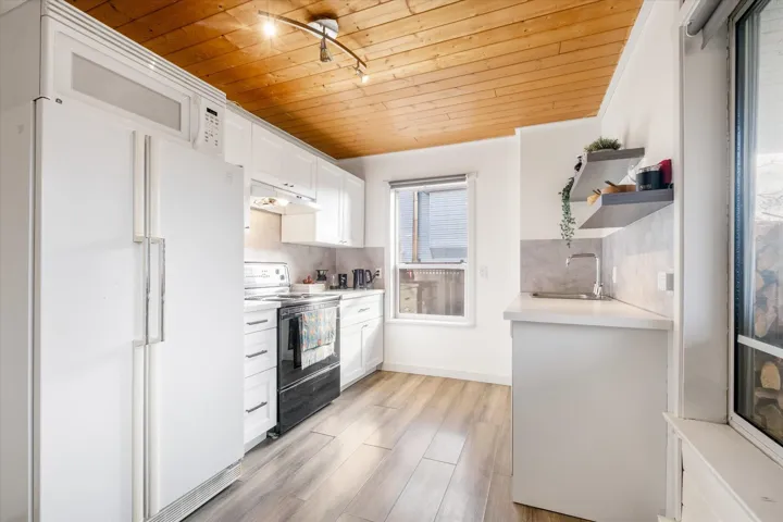 Kitchen featuring white appliances, white cabinets, light countertops, open shelves, and wood ceiling