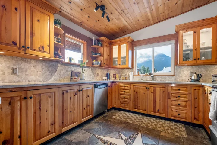 Kitchen featuring open shelves, a vaulted wooden ceiling, wood finish cabinets, stainless steel appliances, and glass fronted cabinets