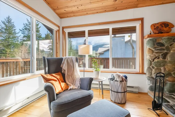Living area with baseboard heating, wood ceiling, light wood-type flooring, a baseboard heating unit, and a fireplace