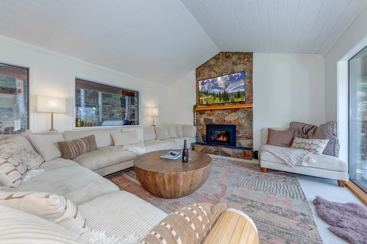 Living room featuring wooden ceiling and a stone fireplace