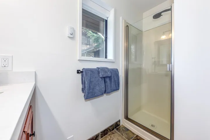 Full bathroom with vanity, a shower stall, and stone finish floors