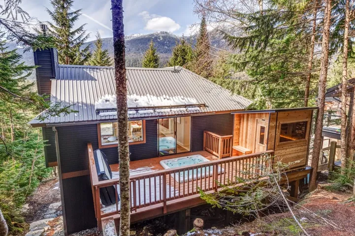 Back of house with a deck with mountain view, a metal roof, and a chimney