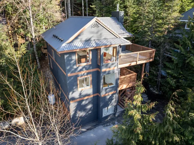 View of outdoor structure featuring an attached garage, a balcony, and view of scattered trees