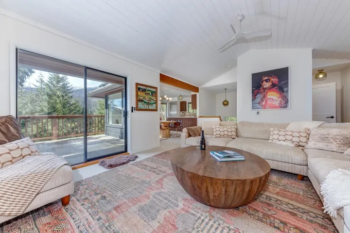 Living area with carpet flooring, a vaulted wood ceiling, and ceiling fan
