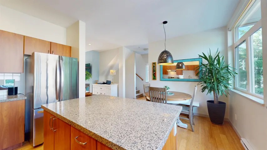 Kitchen featuring light stone countertops, freestanding refrigerator, light wood-type flooring, and a kitchen island