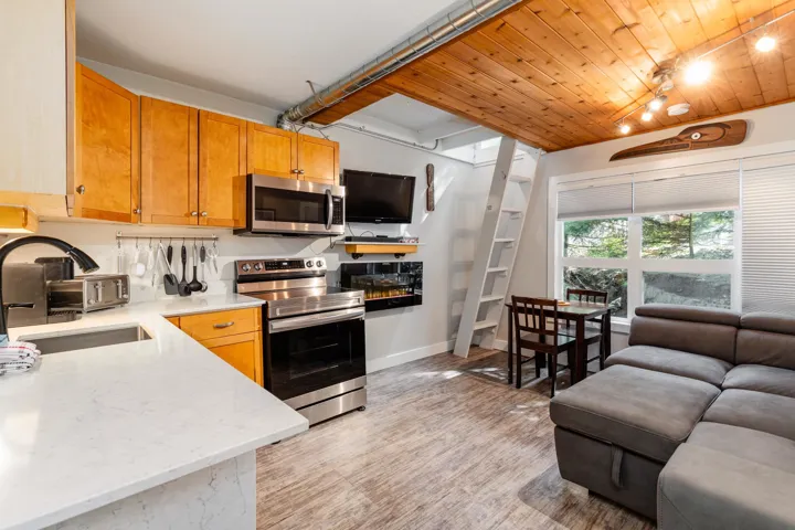 Kitchen featuring stainless steel appliances, rail lighting, light stone countertops, wooden ceiling, and light wood finished floors