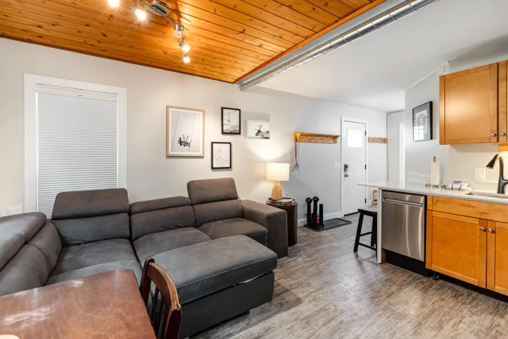 Living room with wood ceiling, light wood-type flooring, and rail lighting